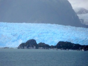 A closer image of the very same glacier.  This photo has not been retouched by software.  The blue hue is similar to any large body of water appearing blue.  All the colors of the spectrum (excepting blue) are absorbed and only the blue is refracted.  Making this more pronounced is that because of the immense pressure to this ice during formation, most of the air is squeezed out.  This air is what give normal ice its white color.