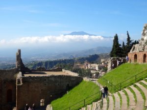 Ancient roman ruins through which Mount Etna is seen.